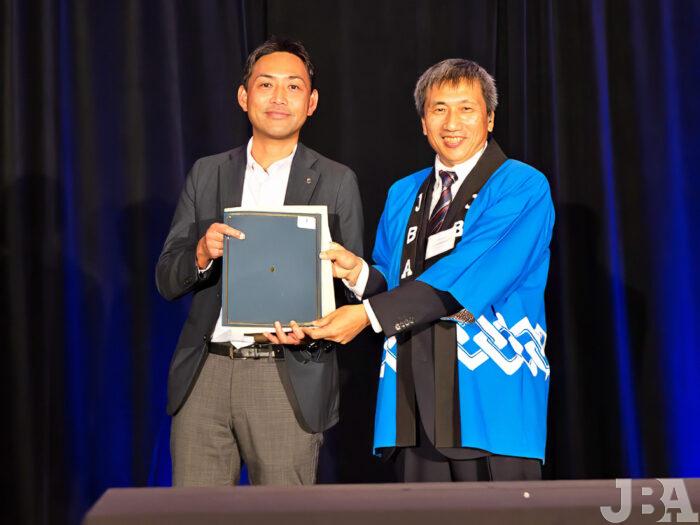 日本航空5万マイルのJAL賞が当選した、KSA America Inc.の丸木さん（左）と梅村企画マーケティング部会長。
